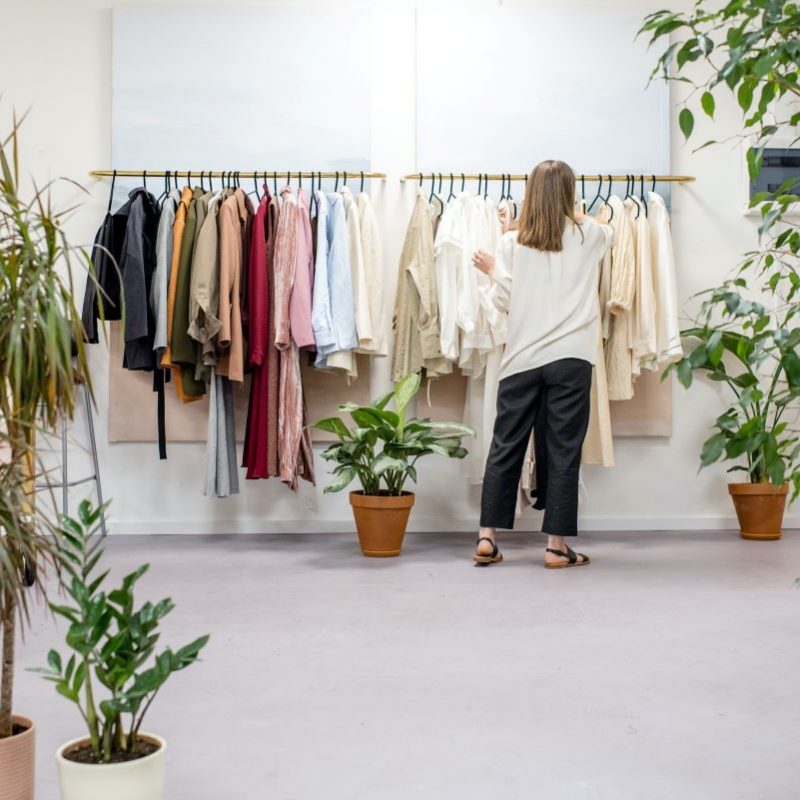 photo d'une femme devant un portant de vêtements dans un magasin