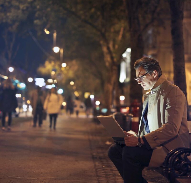 photo d'un homme devant son ordinateur dans la rue